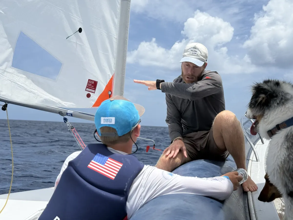 Técnico orientando jovens velejadores do bote de apoio